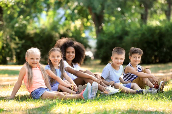 Groep kinderen zitten op gras in park — Stockfoto