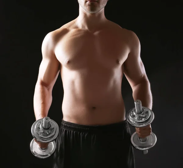 Sporty young man with dumbbells on dark background — Stock Photo, Image