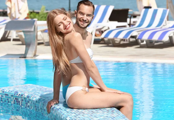 Coppia felice seduta sul bordo della piscina — Foto Stock