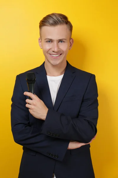 Jeune présentateur avec microphone sur fond couleur — Photo