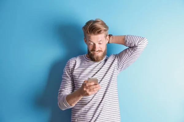 Homem jovem hipster usando smartphone no fundo de cor — Fotografia de Stock