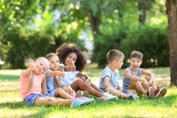 Grupo de niños sentados en el césped en el parque —  Fotos de Stock