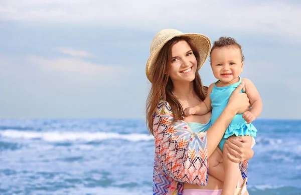 Lycklig mamma med lilla dotter på stranden — Stockfoto