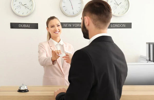 Vrouwelijke receptioniste kaart overhandigen aan klanten in het hotel — Stockfoto