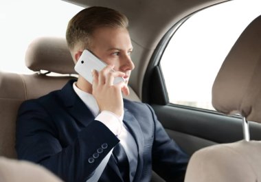 Arabada telefonla konuşan genç işadamı