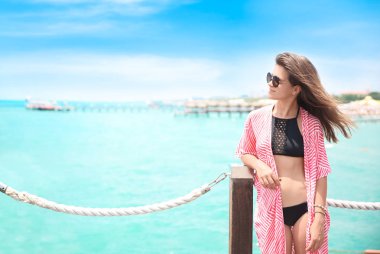Güneşli bir günde iskelede duran güzel kadın