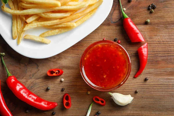 Chilisoße und Teller mit Pommes auf dem Küchentisch — Stockfoto