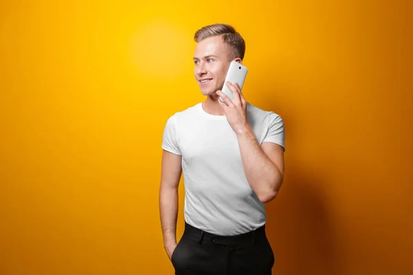Красивий чоловік з телефоном на кольоровому фоні — стокове фото