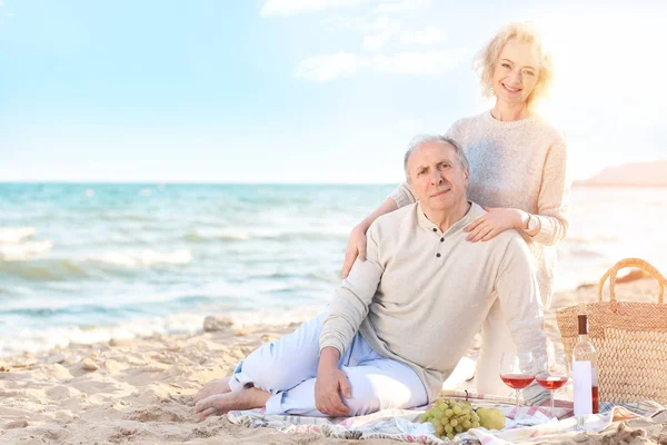 Feliz pareja de ancianos haciendo un picnic en la playa del mar —  Fotos de Stock
