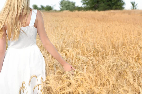 Jonge vrouw aanraken van tarwe in veld — Stockfoto