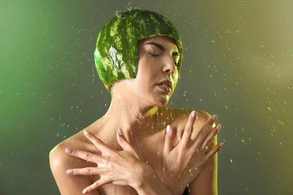 Hälla vatten på kvinnan i vattenmelon hjälm med makeup på färgstarka bakgrund — Stockfoto