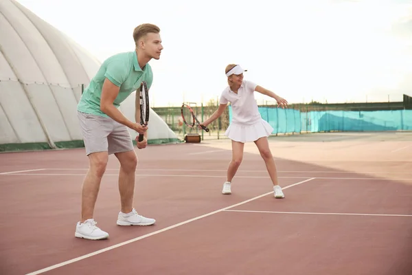 Молодая пара играет в теннис на корте — стоковое фото