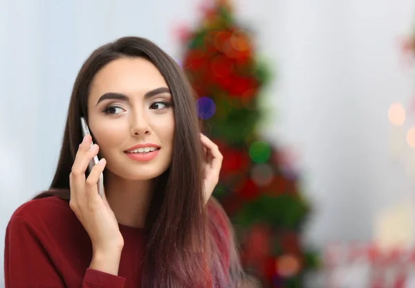 Attraente giovane signora con cellulare su sfondo sfocato di Natale, all'interno — Foto Stock