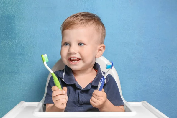 Очаровательный мальчик с двумя зубными щетками на цветном фоне. — стоковое фото