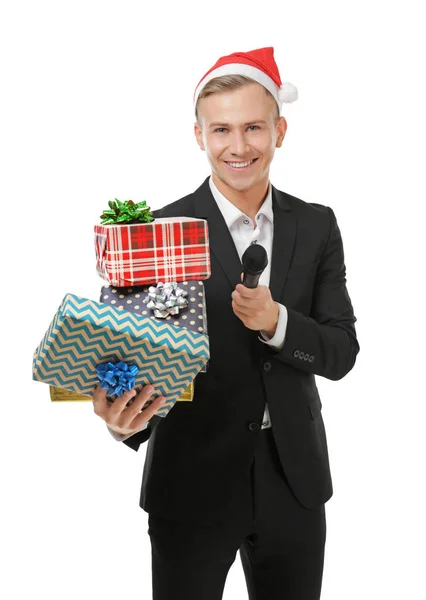 Молодий провідною в Санта hat з мікрофоном і подарункові коробки на білому тлі — стокове фото