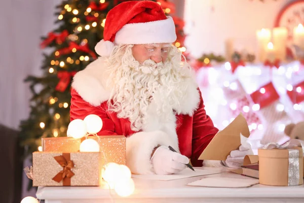 Αυθεντικό Άγιος Βασίλης εργάζεται στο τραπέζι στην αίθουσα διακοσμημένα για τα Χριστούγεννα — Φωτογραφία Αρχείου