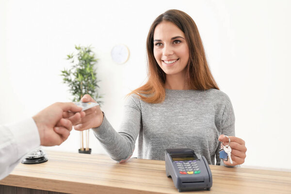 Молодая женщина платит за номер в отеле
