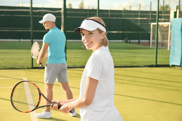 Молодая пара играет в теннис на корте — стоковое фото