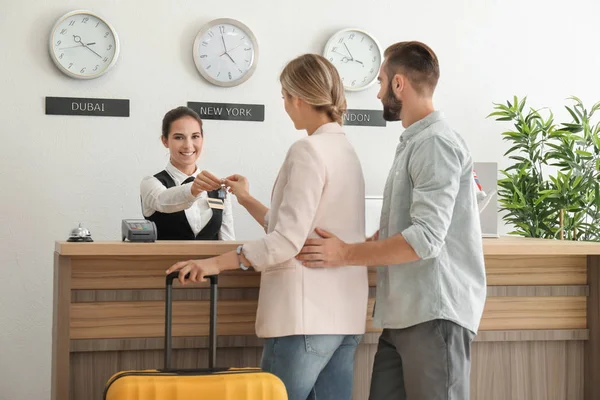 Casal jovem recebendo chave do quarto de hotel na recepção — Fotografia de Stock