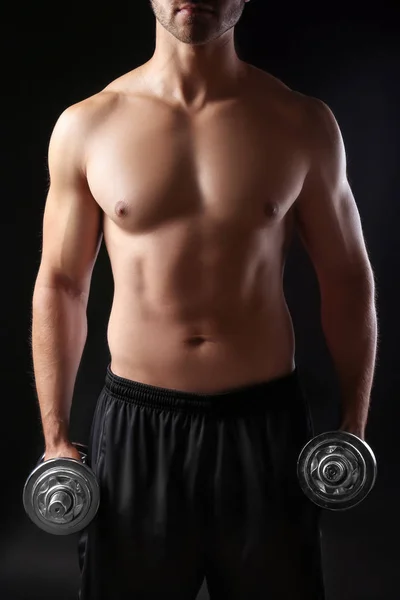 Sporty young man with dumbbells on dark background — Stock Photo, Image