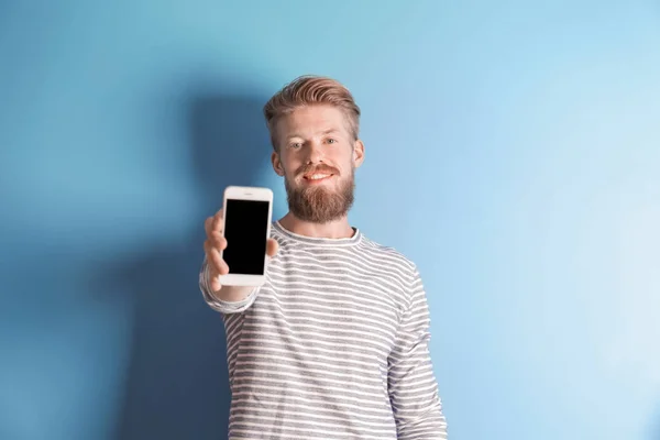 Jovem hipster homem segurando smartphone no fundo de cor — Fotografia de Stock