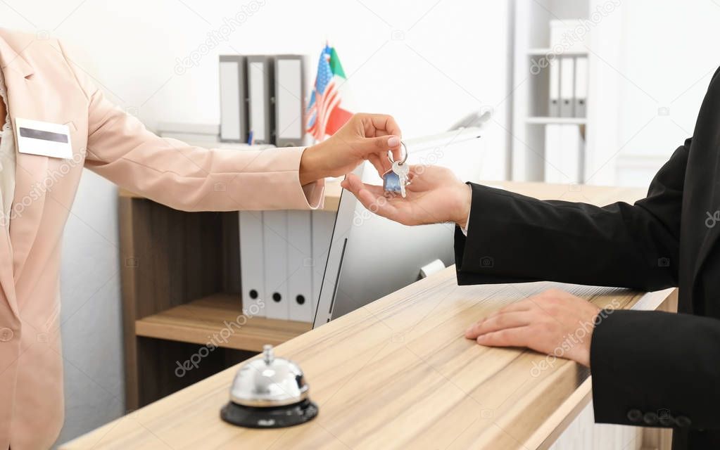 Female receptionist handing room key to customer in hotel