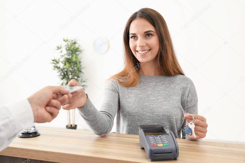 Young woman paying for room in hotel