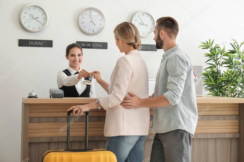 Young couple receiving key from hotel room at reception