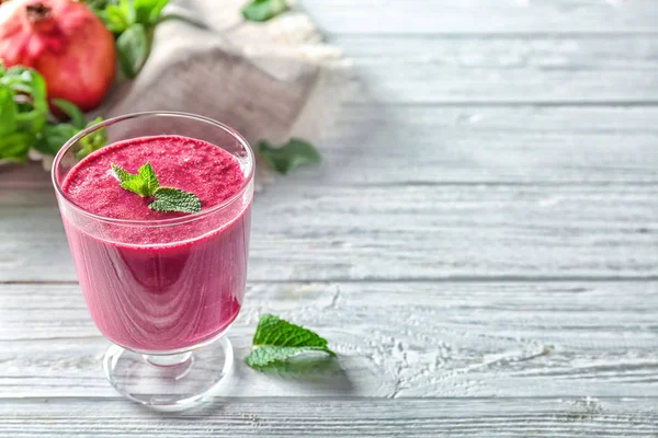 Vidrio con delicioso batido de granada en la mesa — Foto de Stock