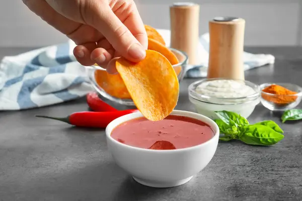 Person doppning potatis chip i chili sås inomhus — Stockfoto