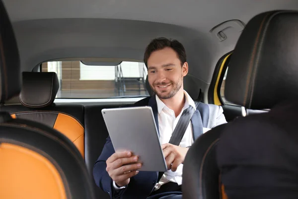 Knappe man met tablet zitten in taxi-auto — Stockfoto