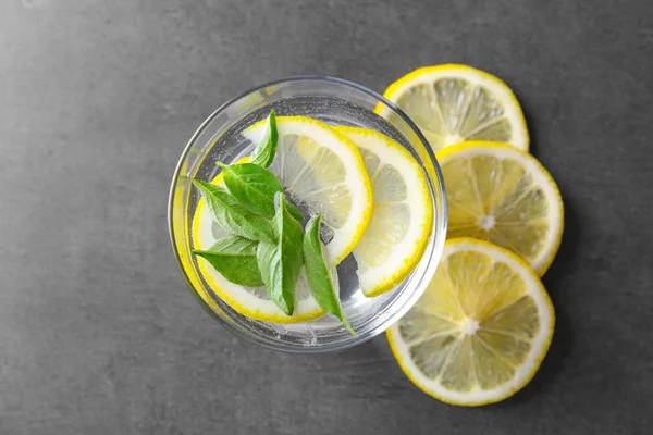 Bicchiere di acqua di basilico e fette di limone sul tavolo — Foto Stock