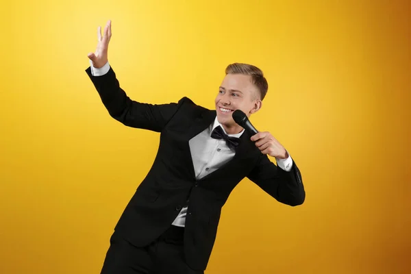 Young presenter with microphone on color background — Stock Photo, Image