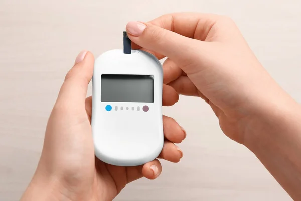 Woman's hands using digital glucometer on light background. Diabetes concept — Stock Photo, Image