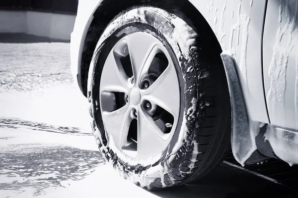 Rueda de automóvil en espuma en el lavado de coches —  Fotos de Stock