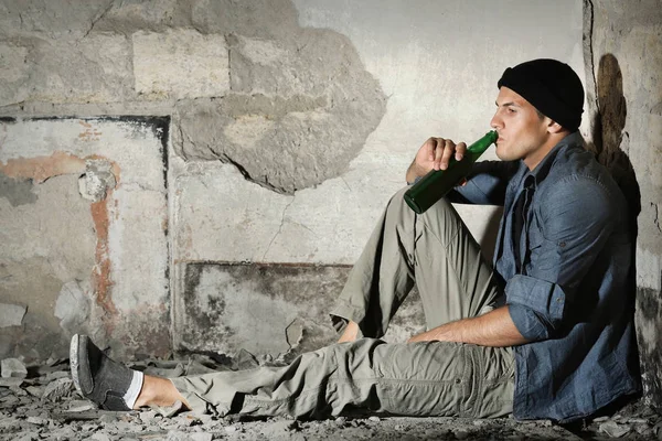 Man sitting and drinking alcohol in abandoned building — Stock Photo, Image