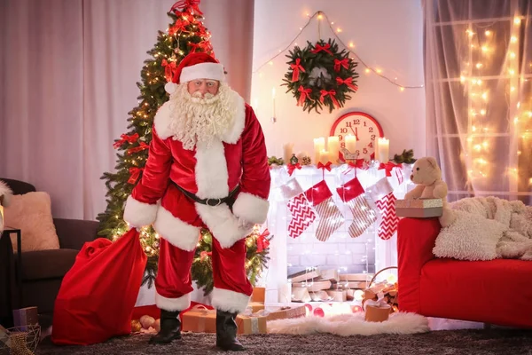 Authentieke Kerstman met grote rode zak vol cadeaus in kamer ingericht voor Kerstmis — Stockfoto
