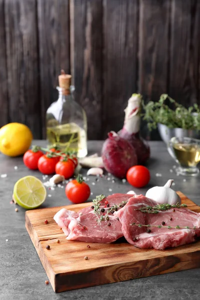 Board with fresh raw steaks and thyme on table — Stock Photo, Image