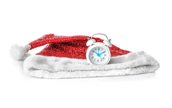 Weihnachtsmann-Hut und kleine Uhr auf weißem Hintergrund. Weihnachts-Countdown-Konzept — Stockfoto