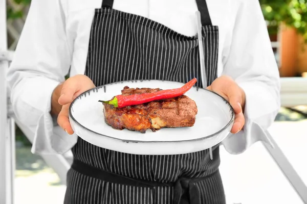 Man holding plate with steak outdoors — Stock Photo, Image