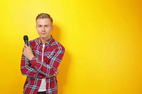 Jeune présentateur avec microphone sur fond couleur — Photo