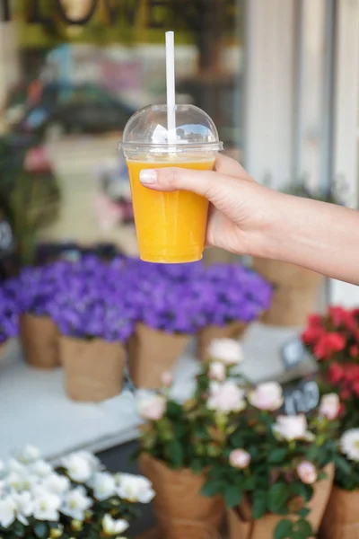 Mujer sosteniendo taza de plástico con jugo — Foto de Stock