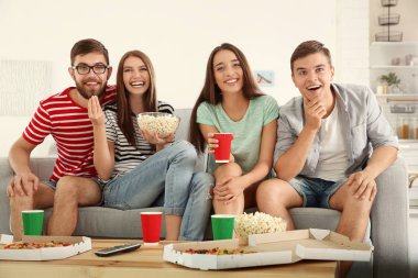 Arkadaşlar evde televizyon izliyor.
