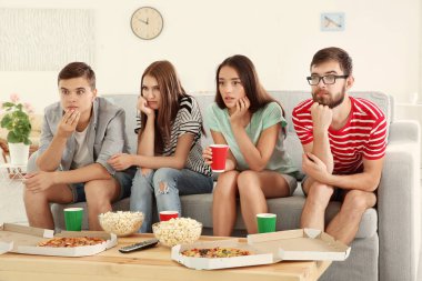 Arkadaşlar evde televizyon izliyor.