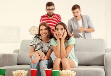 Arkadaşlar evde televizyon izliyor.