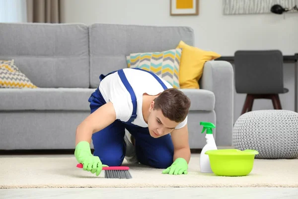 Mann putzt Teppich mit Bürste im Wohnzimmer — Stockfoto