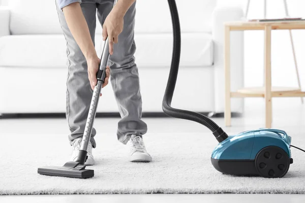 Homme nettoyage tapis blanc avec aspirateur — Photo