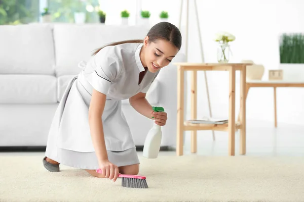 Woman cleaning carpet with brush — Stock Photo, Image