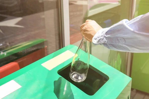 Woman throwing glass bottle into bin — Stock Photo, Image