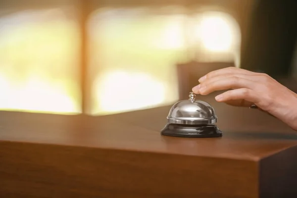 Hand of woman ringing a service bell on reception desk in hotel — Stock Photo, Image